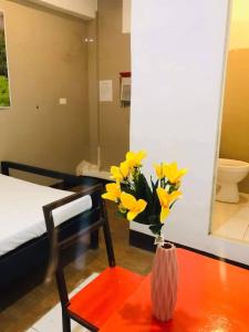 un jarrón de flores amarillas sobre una mesa en un dormitorio en WJV INN BASAK MANDAUE BRANCH, en Mandaue