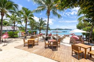 ein Restaurant mit Tischen, Stühlen und Palmen in der Unterkunft Bandara Phuket Beach Resort in Panwa Beach