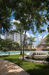 a park with a bench and trees and a pool at Hermoso apartamento piscina, céntrico, área libre. in Cancún