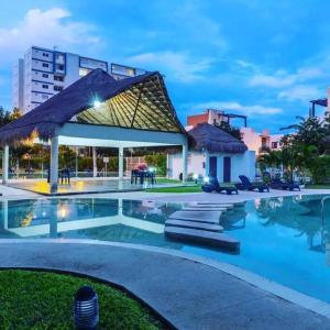a swimming pool with a pavilion and a building at Hermoso apartamento piscina, céntrico, área libre. in Cancún