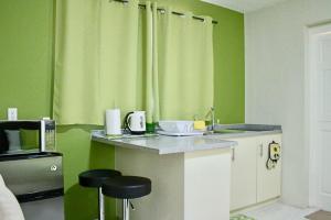 a kitchen with green walls and a counter with stools at Eve's Residence in Willemstad