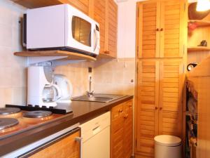 a small kitchen with a microwave and a stove at Appartement Les Carroz d'Arâches, 2 pièces, 6 personnes - FR-1-572-97 in Arâches-la-Frasse