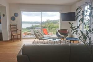uma sala de estar com um sofá e cadeiras e uma grande janela em Rhun Izella - Maison avec vue exceptionnelle - Jacuzzi et Sauna face à la mer em Plougasnou