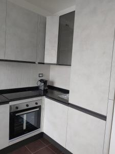 cocina con armarios blancos y fogones en Milano Santa Giulia Business Apartment - Olimpiadi 26 en Milán