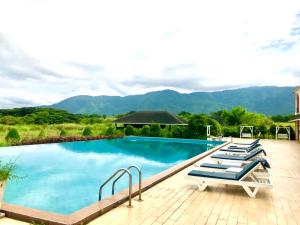 a swimming pool with lounge chairs and mountains in the background at Aurora Resort Khao Yai in Mu Si