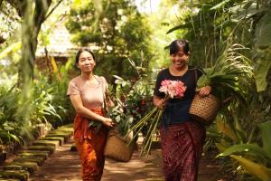 twee vrouwen die door een tuin lopen met planten bij Sang Natha in Tjatur
