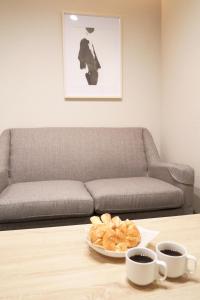 a table with a couch and two cups of coffee at Koti Sopo Universal Bay 4 by Liaison in Osaka