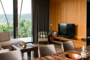 a living room with a television and a table with chairs at Atta Lakeside Resort Suite - SHA Plus Certified in Mu Si