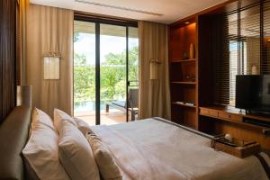 a bedroom with a bed and a tv and a window at MUTHI MAYA Forest Pool Villa Resort - SHA Plus Certified in Mu Si