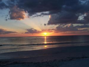 een zonsondergang op het strand met zonsondergang bij Tropical Beach Resorts - Sarasota in Sarasota