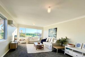 Una sala de estar con un sofá blanco y una ventana grande. en Beautiful 4-bedroom original beach cottage in Port Kembla, en Port Kembla