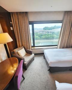 ソウルにあるNiagara Hotelのベッド、テーブル、窓が備わる客室です。