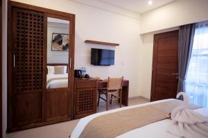 a bedroom with a bed and a desk with a television at Kayu Sugih Palace in Sanur