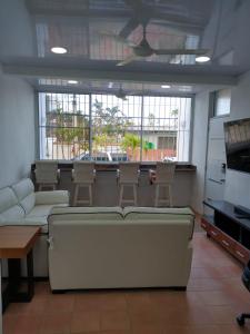 uma sala de estar com um sofá, cadeiras e janelas em Sosua Apartment 4-Bedrooms em Sosúa