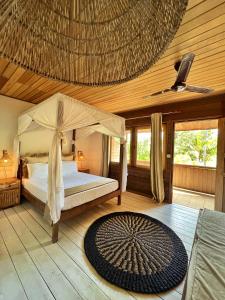 a bedroom with a bed with a canopy and a rug at Iru Maldives in Thulusdhoo