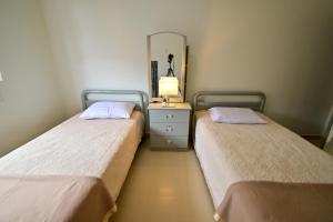 2 camas en una habitación con tocador y espejo en D'Ja Smoke Homestay, en Kampong Wakaf Tengah