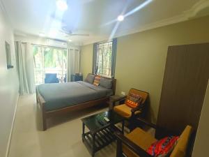 a bedroom with a bed and a couch and a chair at Kanvas Suites - Sun N Moon in Palolem