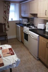 a kitchen with white appliances and a table in it at Bridge House in Glenties