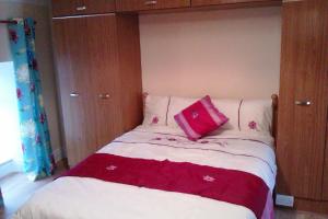 a bed with a red pillow on top of it at Bridge House in Glenties