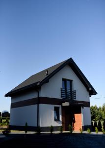 a white house with a black roof at Nova 26 in Klucze