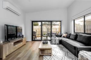 a living room with a couch and a flat screen tv at The house with the orange door Inverloch in Inverloch