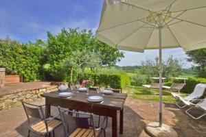 a wooden table with chairs and an umbrella at Pozzovecchio - Happy Rentals in Casole dʼElsa
