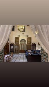 梅克內斯的住宿－Riad Dar AlKATIB Meknès，配有窗帘和桌子以及吊灯的房间