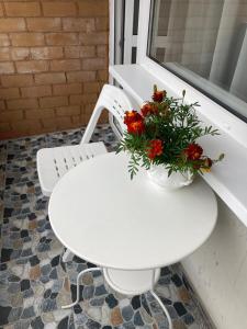 een witte tafel met een vaas met bloemen erop bij Nameja Best view apartamenti in Jēkabpils