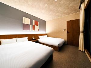 那覇市にあるRakuten STAY 那覇 美栄橋 スイートルームのベッド2台が備わるホテルルーム内のベッド2台