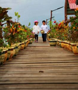 duas pessoas a descer uma passarela de madeira com flores em Pavalintang Resort em Semporna