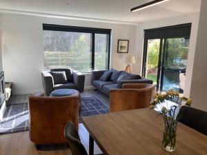 uma sala de estar com um sofá, cadeiras e uma mesa em Garden Apartment em Queenstown