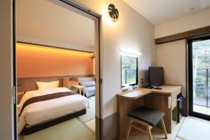 a bedroom with a bed and a desk and a television at KusatsuOnsen AeruyadoTakamatsu in Kusatsu