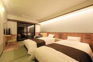 a hotel room with two beds and a television at KusatsuOnsen AeruyadoTakamatsu in Kusatsu