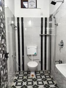 a bathroom with a toilet and a black and white tile floor at joseys homestay in Cochin