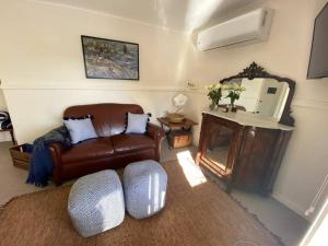 a living room with a leather couch and a mirror at Farm Cottage close to Dubbo in Dubbo