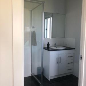 a bathroom with a sink and a shower with a mirror at CandE on Samphire in Kingscote