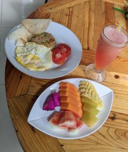 two plates of food on a wooden table with a drink at Ubud Dream in Ubud