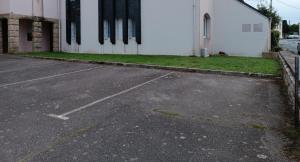 an empty parking lot next to a white building at Loc'Eric in Pont-lʼAbbé