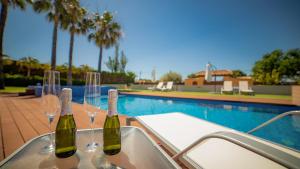 zwei Weinflaschen und Gläser auf einem Tisch neben einem Pool in der Unterkunft Hotel Boutique Canelobre in Busot