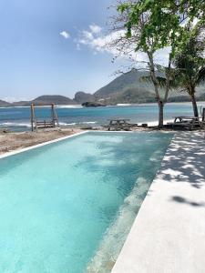 uma piscina ao lado de uma praia com o oceano em Kacchapa Beach Resort and Restaurant em Sekongkang
