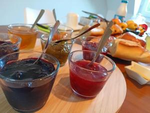 una mesa con cuatro vasos de mermelada y salsa en Les chambres du Vert Galant Rez de jardin, en Verlinghem