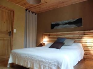 a bedroom with a white bed with a wooden wall at Gite et cabane écologiques 1000 Pailles in Labastide-de-Virac