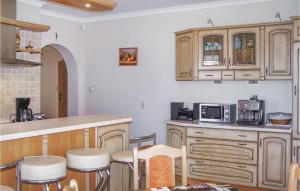 una cocina con armarios de madera y una barra con taburetes en Amazing Home In Rowy With 4 Bedrooms, en Rowy