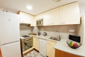 a small kitchen with white cabinets and a sink at Little Home Girona in Girona