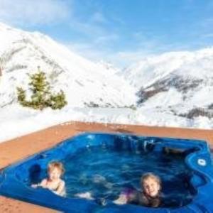 Dos niños en una bañera de hidromasaje con montañas al fondo en BAITA NOEMI, en Livigno