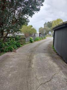 an empty road with a fence and a house at Rural in the city in Palmerston North