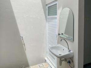 ein weißes Badezimmer mit Waschbecken und Spiegel in der Unterkunft RedDoorz Plus at Orange Diponogoro Palangkaraya in Palangkaraya + 23 Fotos