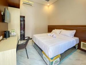 een slaapkamer met een bed en een stoel in een kamer bij RedDoorz Plus @ Orange GH Diponogoro in Palangkaraya