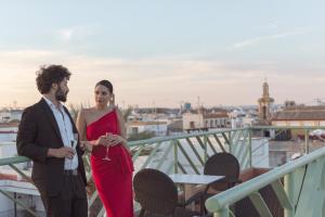 Un uomo e una donna in piedi su un balcone di Casa Romana Hotel Boutique a Siviglia