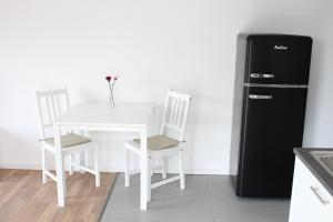 una cucina con tavolo bianco e frigorifero nero di Rendel-Apartments by Bismarck Hostel Öhringen a Öhringen